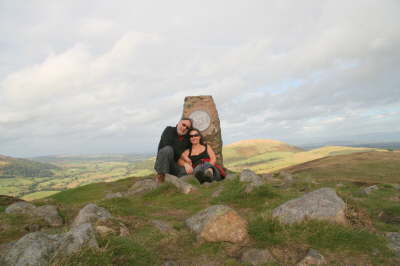 Derek & Suzanne sheltering behind Trig Point